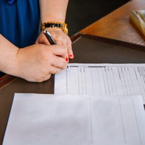 person holding pen and writing on paper