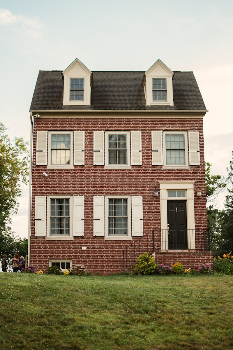 a red brick house with white shutters and a black roof